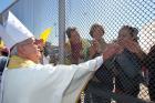 Bishop Mark J. Seitz of El Paso, Texas, touches the hands of people in Mexico through a border fence following Mass in Sunland Park, N.M., in this 2014 file photo. (CNS photo/Bob Roller)