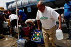 A man carries containers filled with water from a tank truck in Canovanas, Puerto Rico, Sept. 26 (CNS photo/Carlos Garcia Rawlins, Reuters). 