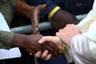 Pope Francis shakes hands with a man as he visits a migrant reception centre during a pastoral visit in Bologna, Italy, Oct. 1. The pope is seen wearing a yellow ID bracelet with his name and a number, just like the immigrants and refugees at the center. (CNS photo/Alessandro Bianchi, Reuters)