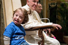 A young girl sitting next to Pope Francis smiles during an audience with Special Olympics athletes participating in the Unified Football tournament, at the Vatican Oct. 13. (CNS photo/L'Osservatore Romano)