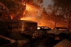 Burned cars are seen on a piece of property Dec. 5 during a wildfire near Santa Paula, Calif. Pushed by powerful Santa Ana winds, the fire spread with explosive speed to 31,000 acres in Southern California's Ventura County, forcing thousands to evacuate in the dark. (CNS photo/David McNew, Reuters)