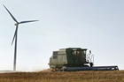 A combine harvests wheat near a wind turbine close to Lincoln, Kan., in this 2008 file photo. Two religious communities were pleased that two Midwest utilities recently agreed to publish climate risk assessment reports in alignment with the Paris climate accord. (CNS photo/Larry W. Smith, EPA) See SHAREHOLDERS-CLIMATE March 2, 2018.