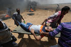 A wounded Palestinian is evacuated at the Israel-Gaza border during a protest against the U.S. embassy move to Jerusalem May 14. (CNS photo/Ibraheem Abu Mustafa, Reuters)