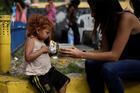 A volunteer with "Make the Difference" charity initiative gives a cup of soup and an "arepa" to a homeless child along a street in Caracas, Venezuela, March 5, 2017. Caracas in recent years has seen tear gas attacks, physical assaults on citizens by government forces, and hungry and malnourished crowds asking for help in streets that once boasted some of the most well-off people in all of Latin America. (CNS photo/Marco Bello, Reuters)