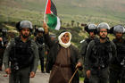 A demonstrator holding a Palestinian flag stands amid Israeli border police during a protest against Israeli settlements and U.S. President Donald Trump's Middle East peace plan. The protest was in the Jordan Valley, part of the Israeli-occupied West Bank, Feb. 25, 2020. (CNS photo/Raneen Sawafta, Reuters)