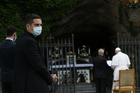 A cleric wears a mask as Pope Francis leads the recitation of the rosary during a prayer service at the Lourdes grotto in the Vatican Gardens on May 30. (CNS photo/Paul Haring) 