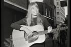 Joni Mitchell strums guitar outside the The Revolution Club, London, England, Sept. 17, 1968 (Alamy).