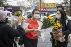 Roula AbiSamra, center, and Chelsey, right, prepare to lay flowers bouquets at a makeshift memorial outside of the Gold Spa in Atlanta, one of the sites of a shooting spree that killed eight people in the Atlanta area this Tuesday. (Alyssa Pointer/Atlanta Journal-Constitution via AP, File)