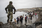 People mainly from Morocco stand on the shore as the Spanish Army cordons off a beach at the border of Morocco and Spain in the Spanish enclave of Ceuta on May 18. Ceuta faced a humanitarian crisis after thousands of Moroccans took advantage of relaxed border control in their country to swim or paddle in inflatable boats into European soil. (AP Photo/Javier Fergo)