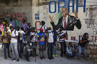 Journalists gather near a mural featuring Haitian President Jovenel Moise, near the leader’s residence where he was killed by gunmen in the early morning hours, and his wife was wounded, in Port-au-Prince, Haiti, Wednesday, July 7, 2021. (AP Photo/Joseph Odelyn)