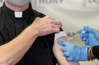 A Catholic pastor receives the first of the two Pfizer-BioNTech COVID-19 vaccinations 