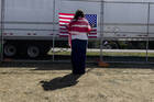 A woman prays as she faces a U.S. flag on a perimeter fence