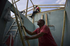 In this Nov. 15 photo, Pedro Deschamps helps workers hired by FEMA to carry out the installation of a temporary awning roof at his house, which suffered damage during Hurricane Maria, in San Juan, Puerto Rico. (AP Photo/Carlos Giusti)