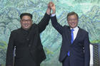 In this image made from video provided by Korea Broadcasting System (KBS), North Korean leader Kim Jong Un, left, and South Korean President Moon Jae-in raise their hands after signing on a joint statement at the border village of Panmunjom in the Demilitarized Zone Friday, April 27, 2018. (Korea Broadcasting System via AP)