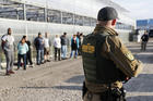 Government agents stand guard alongside suspects taken into custody during an immigration sting at Corso's Flower and Garden Center, Tuesday, June 5, 2018, in Castalia, Ohio. The operation is one of the largest against employers in recent years on allegations of violating immigration laws. (AP Photo/John Minchillo)