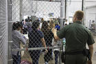 A U.S. Border Patrol agent watches as people who've been taken into custody related to cases of illegal entry into the United States, stand in line at a facility in McAllen, Texas, Sunday, June 17, 2018. (U.S. Customs and Border Protection's Rio Grande Valley Sector via AP)