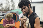 In this Oct. 23, 2018 photo, Ronald Lauricella cradles a kitten in his front yard in Bay County, Fla. The rural Bay County resident says some on the outskirts of the cities aren't getting needed services like electricity as fast as the populated areas. (AP Photo/Tamara Lush)