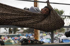 A migrant rests inside a blanket tied to keep him from rolling off the spectator stands at the Benito Juárez Sports Complex in Tijuana, Mexico. (AP Photo/Rebecca Blackwell)