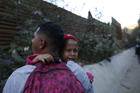 A Honduran migrant carries Jired Melendez, 4 years-old, as they try to cross over the U.S. border wall to San Diego, California, from Tijuana, Mexico, Saturday, Dec. 15, 2018. (AP Photo/Moises Castillo)