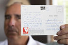 James Grein, 61, at his house in Sterling, Va., Friday, July 26, 2019, holds a Florida postcard sent to him when he was 15 years old by now-defrocked Cardinal Theodore McCarrick. Letters and postcards from McCarrick wrote to three men he allegedly sexually abused and harassed show how he groomed his victims, experts say. (AP Photo/Manuel Balce Ceneta)