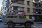 Residents stand on a balcony as a South African National Defence Forces vehicle patrol the street, in Johannesburg on April 7. South Africa and more than half of Africa's 54 countries have imposed lockdowns, curfews, travel bans or other restrictions to try to contain the spread of COVID-19. (AP Photo/Themba Hadebe)