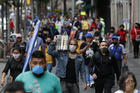 Shoppers and commuters walk along a sidewalk in central Mexico City, on July 6, 2020. After three months of shutdown, officials allowed a partial reopening of the downtown commercial area last week, although COVID-19 cases continue to climb. (AP Photo/Rebecca Blackwell)