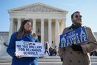 People hold signs outside the U.S. Supreme Court in Washington Jan. 22, 2020, ahead of oral arguments in a case from Montana on religious rights and school choice. The court is examining if states should give aid, in the form of tax credits, to private religious schools. (CNS photo/Sarah Silbiger, Reuters)