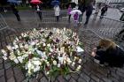 A woman places a candle by floral tributes for the victims of an attack at Turku Market Square on Friday, in Turku, Finland, Saturday, Aug. 19, 2017. (Vesa Moilanen/Lehtikuva via AP)