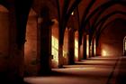 A dim corridor lined with heavy arches