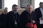 Two Catholic priests sit side by side wearing black clerical robes