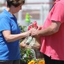 A volunteer in a blue shirt hands a plastic bag of potatoes to a person in need at a food pantry in July 2021.